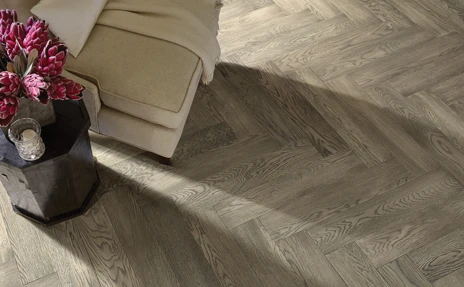 Herringbone hardwood floor with cream chair and flowers 